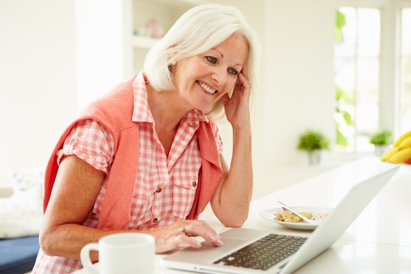 over 50 age woman laughing during online dating at laptop